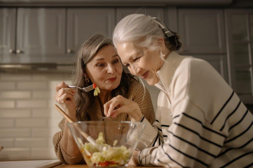 Une femme âgée mangeant une salade dans la cuisine